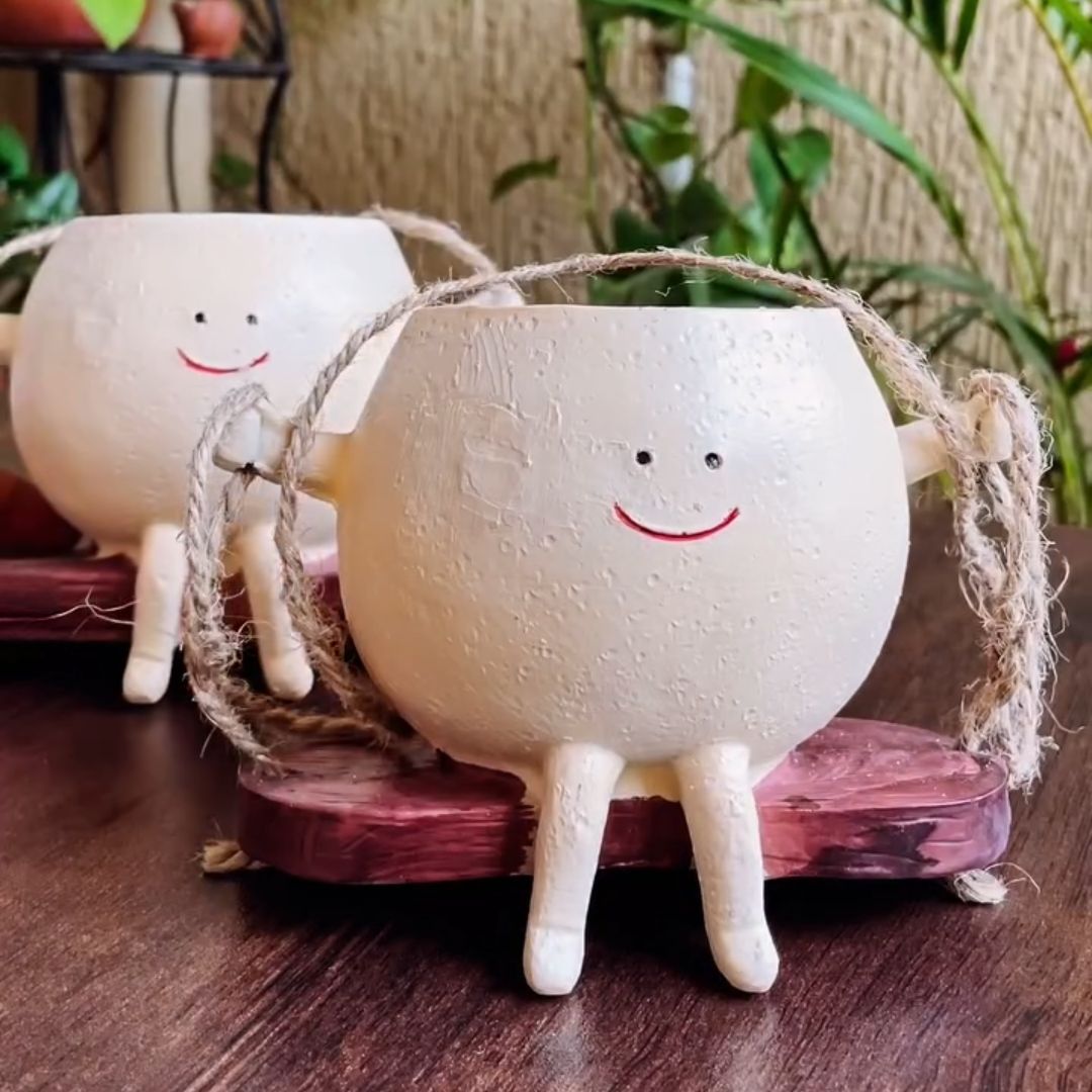 Two white ceramic sheep figurines with smiling faces on a wooden surface.