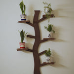 Wall-mounted tree-shaped wooden shelf with potted indoor plants in decorative planters