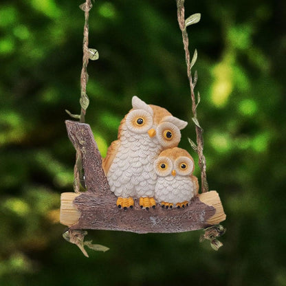 Two owl figurines on a branch against a blurred green background