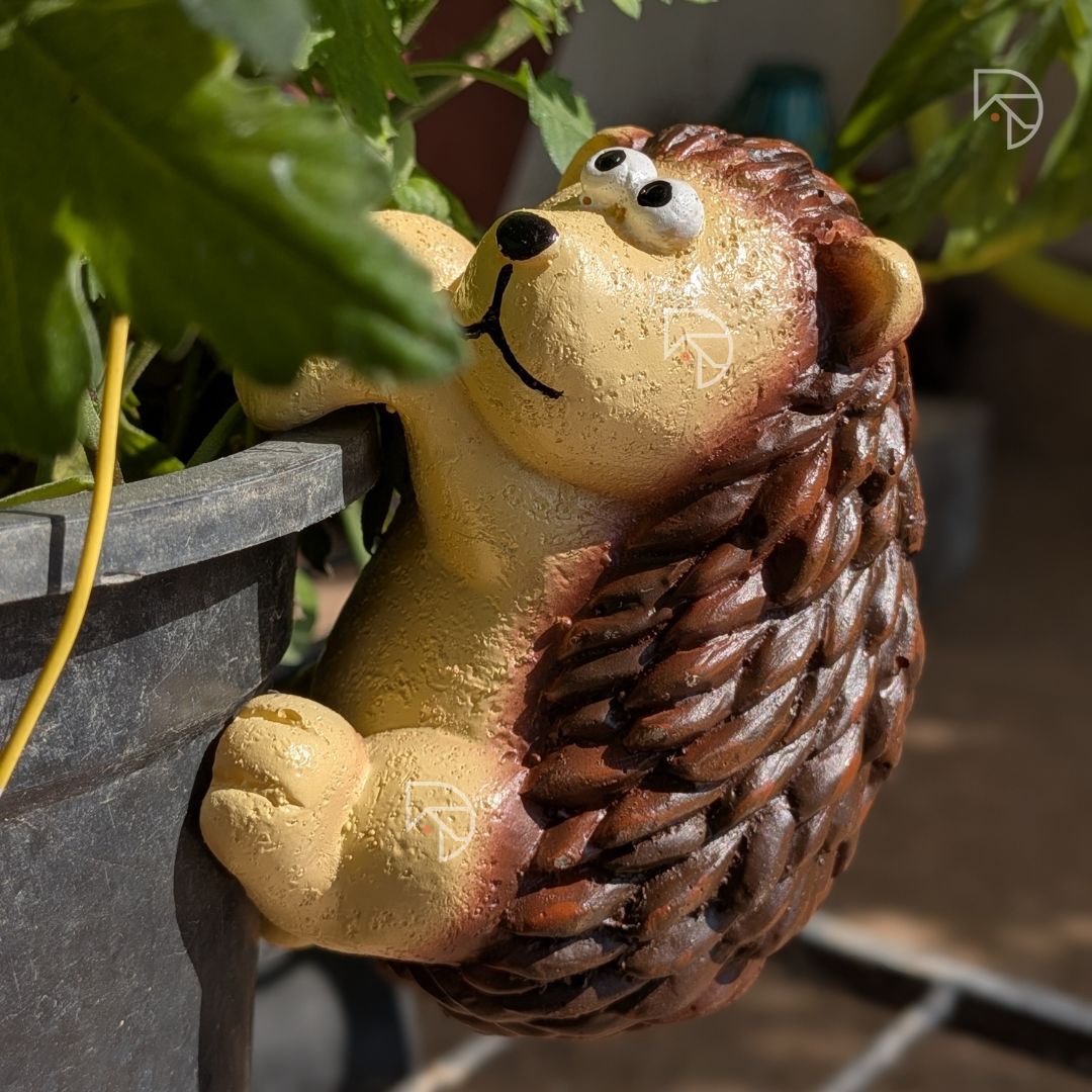 Hedgehog pot rim hanger front view — cream yellow face with black eyes and painted smile on balcony planter