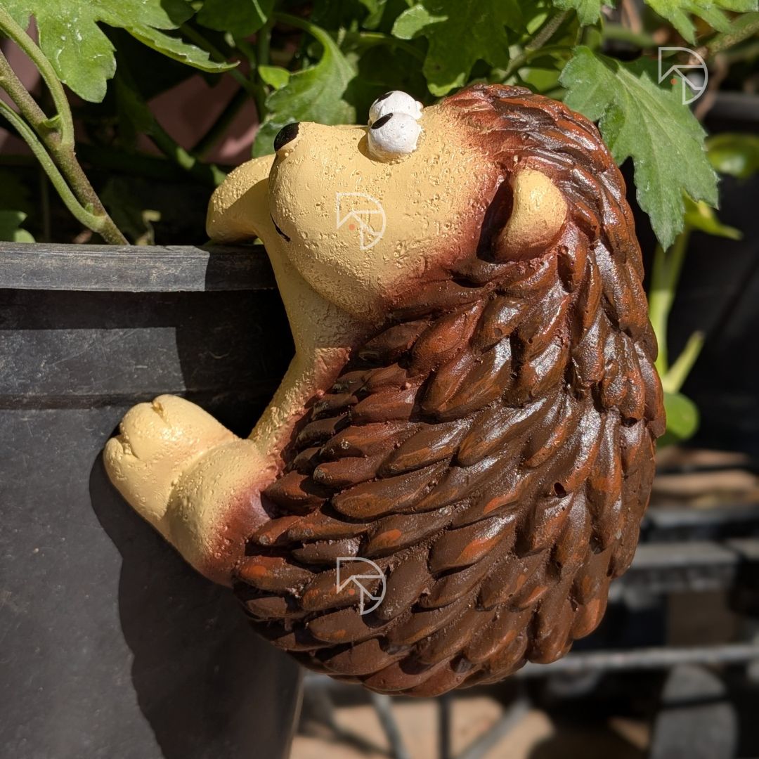 Hanging hedgehog figurine on dark garden pot — full body view showing two-tone cream and brown finish