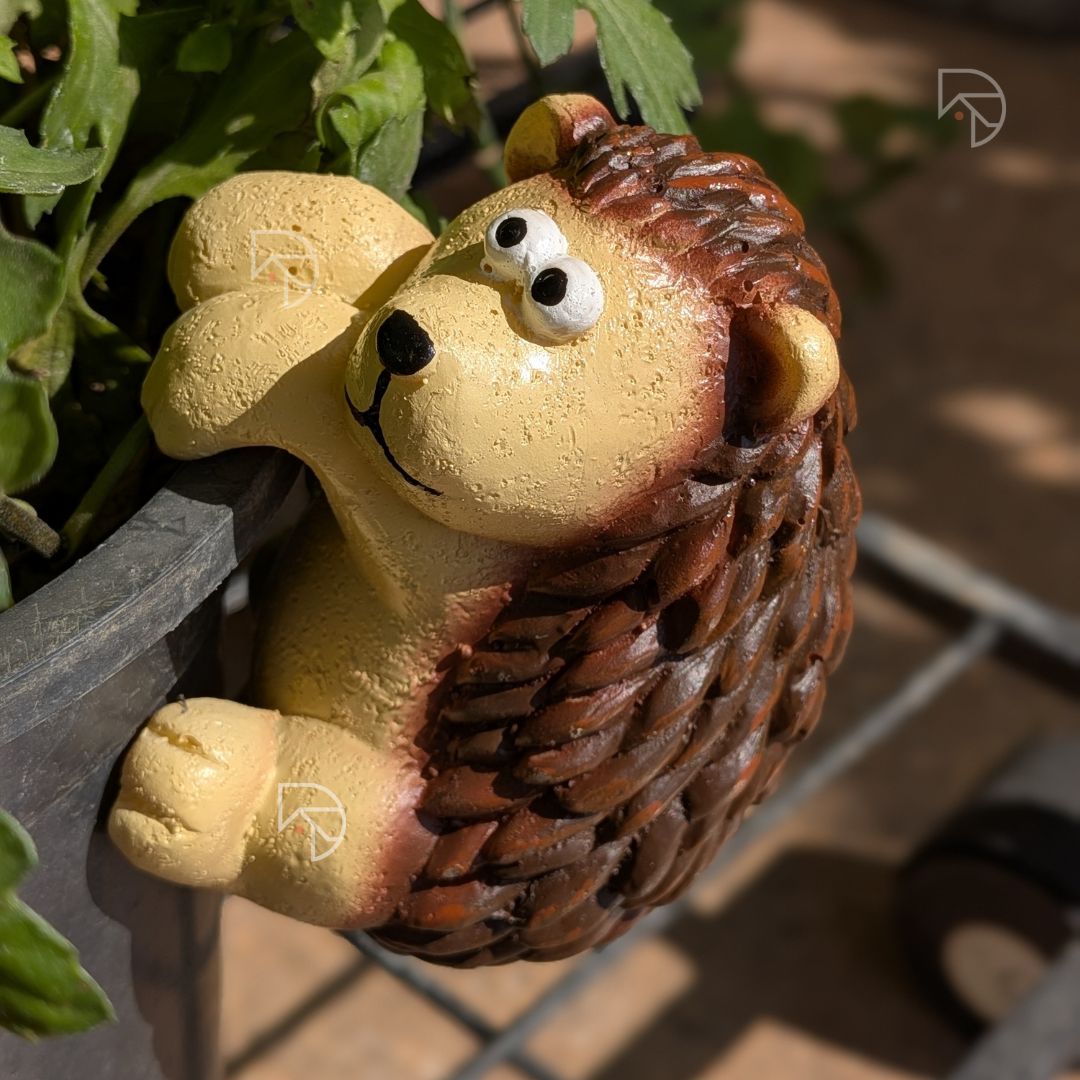 Hanging hedgehog resin figurine gripping garden pot rim — side view showing spine detail and dangling legs