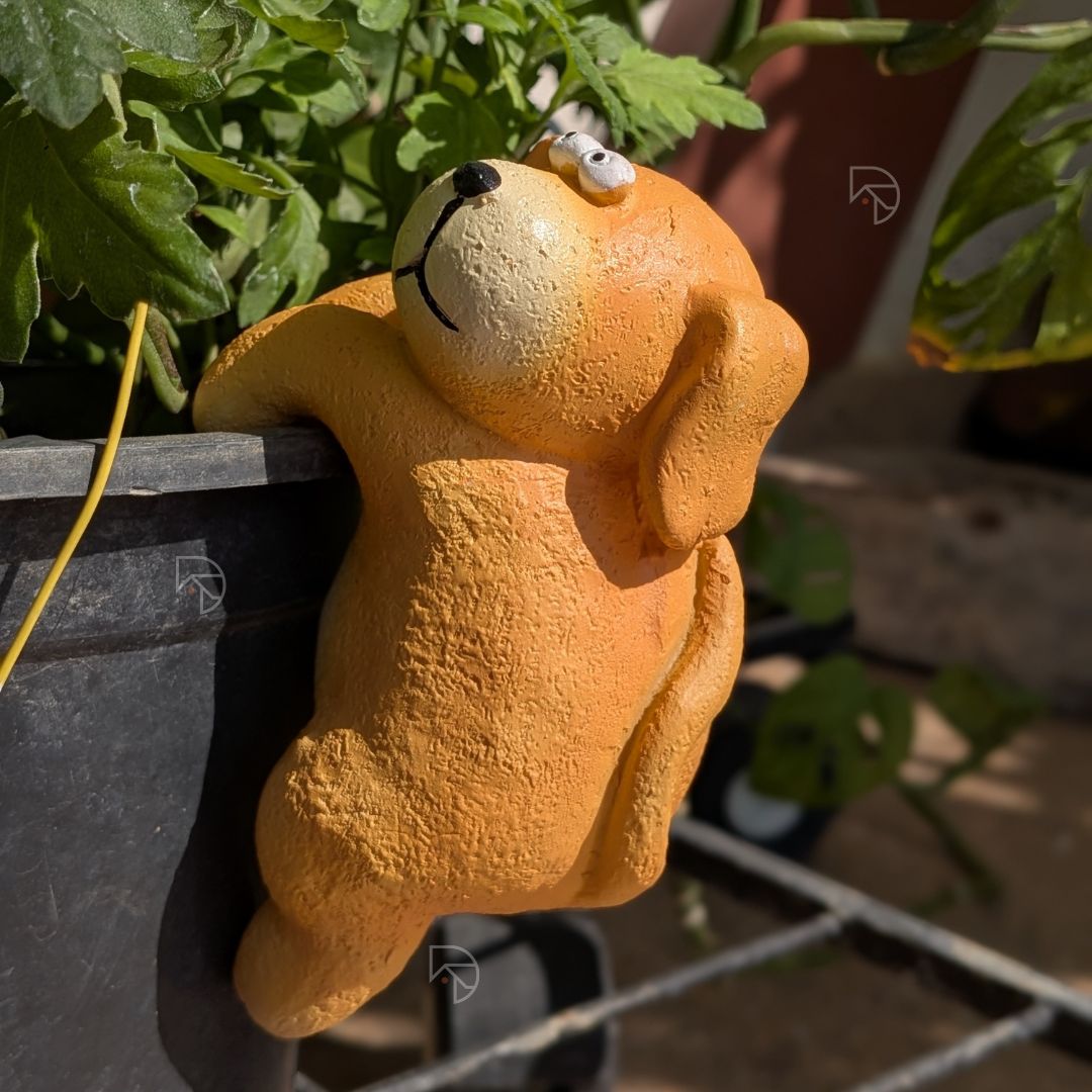 Close-up of hanging dog garden figurine face — cream muzzle, black nose, expressive eyes