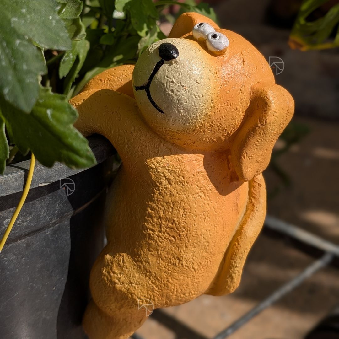 Orange climbing dog figurine gripping pot rim — cute garden decor ornament for plant lovers