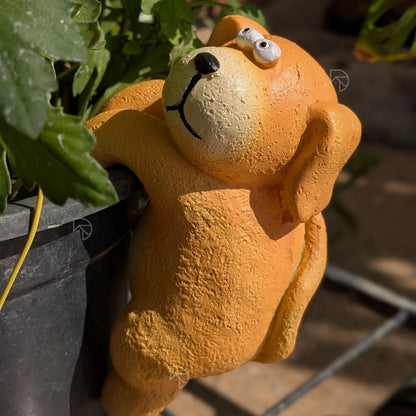 Orange climbing dog figurine gripping pot rim — cute garden decor ornament for plant lovers