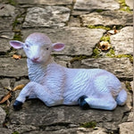 White sheep figurine lying on a stone surface