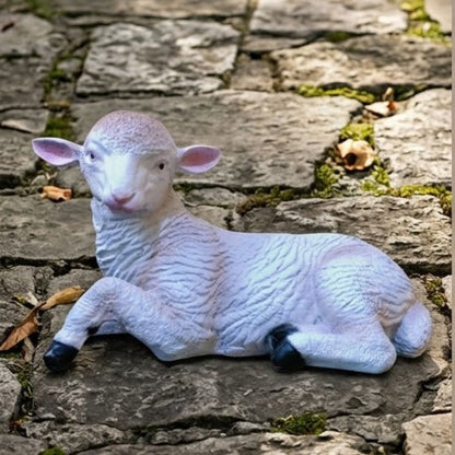 White sheep figurine lying on a stone surface