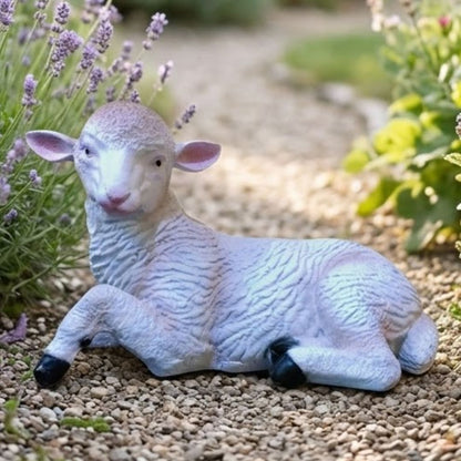 Decorative sheep figurine on a pebble path with plants in the background