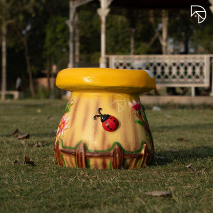 Decorative garden stool with a yellow top and colorful design on grass