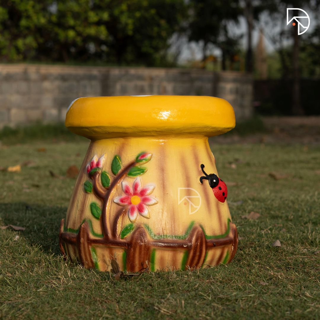 Decorative outdoor stool with floral and ladybug design on grass