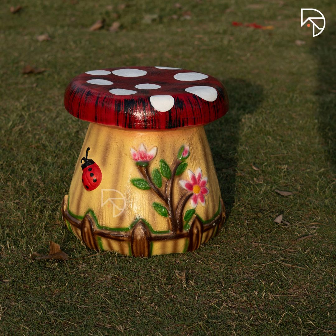 Decorative mushroom-shaped stool with floral and ladybug design on grass