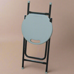 White round stool with black metal frame against a textured wall.
