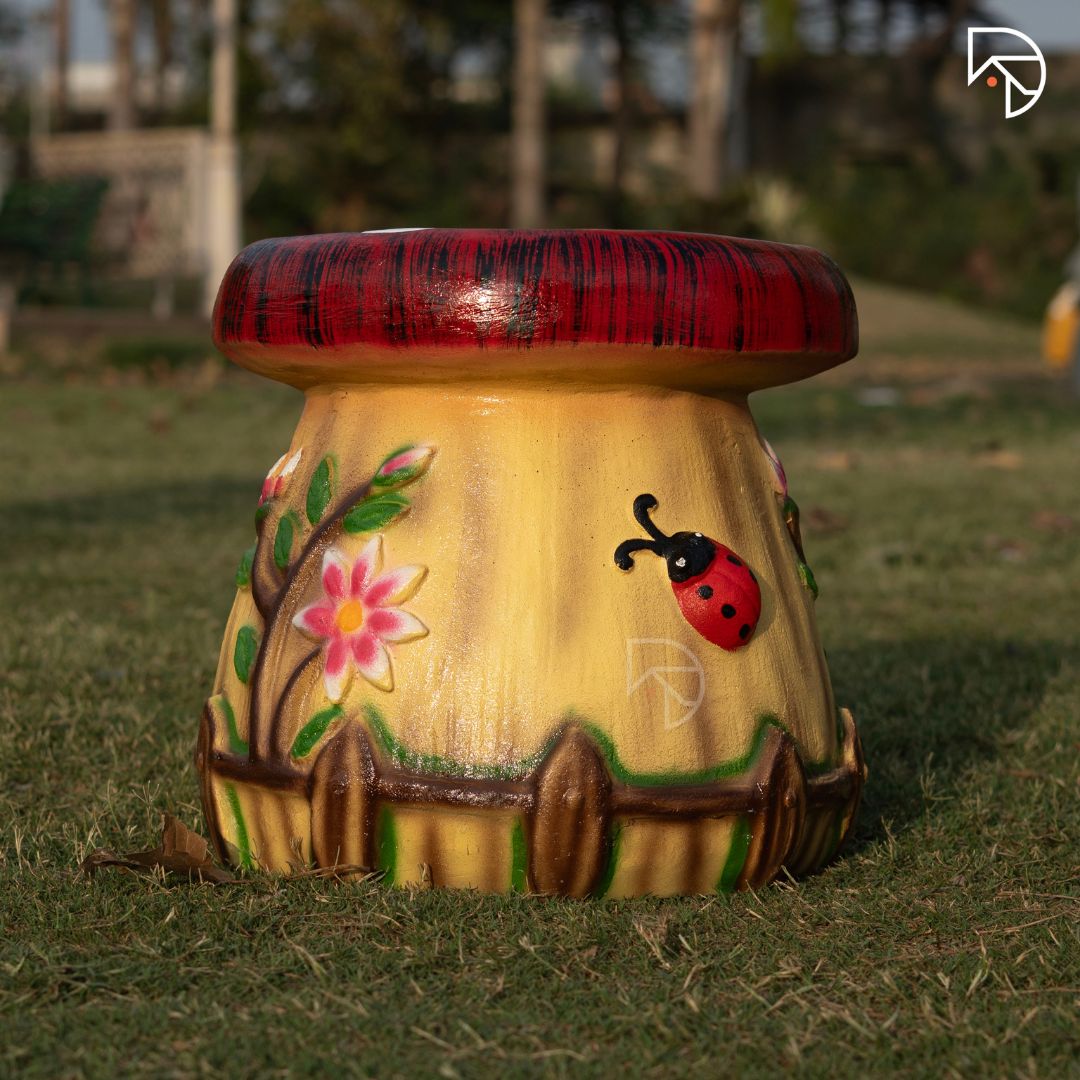 Decorative mushroom-shaped stool with floral and ladybug design on grass