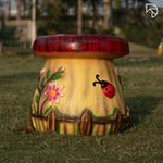 Decorative mushroom-shaped stool with floral and ladybug design on grass