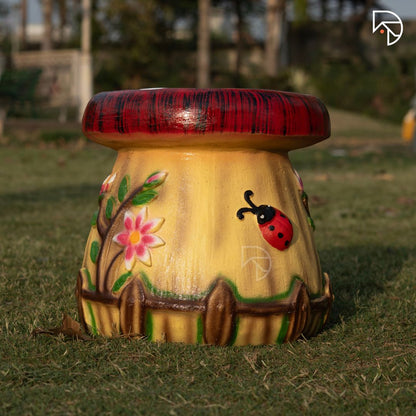 Decorative mushroom-shaped stool with floral and ladybug design on grass
