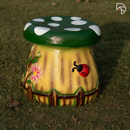 Decorative mushroom-shaped stool with a green cap and yellow body on grass