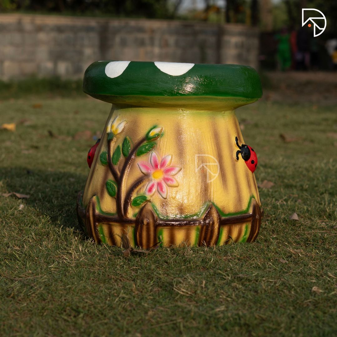 Decorative garden stool with floral and ladybug design on grass