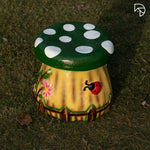 Decorative mushroom-shaped stool with a green cap and white spots on a grassy background.