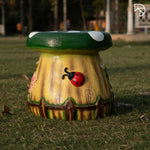 Decorative mushroom-shaped bench with a ladybug design on grass