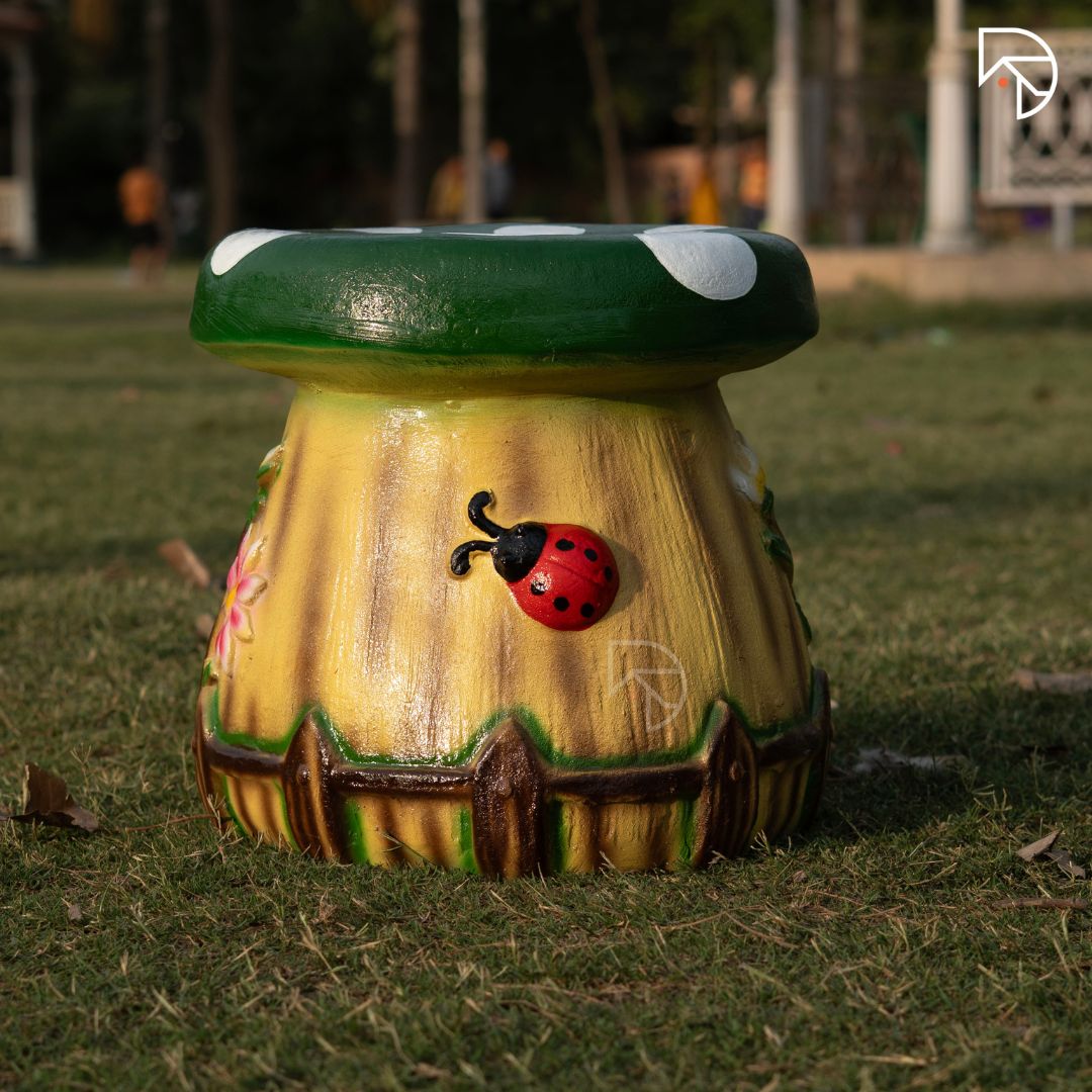 Decorative mushroom-shaped bench with a ladybug design on grass