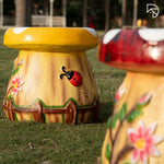 Decorative garden stool with floral and ladybug design on grass