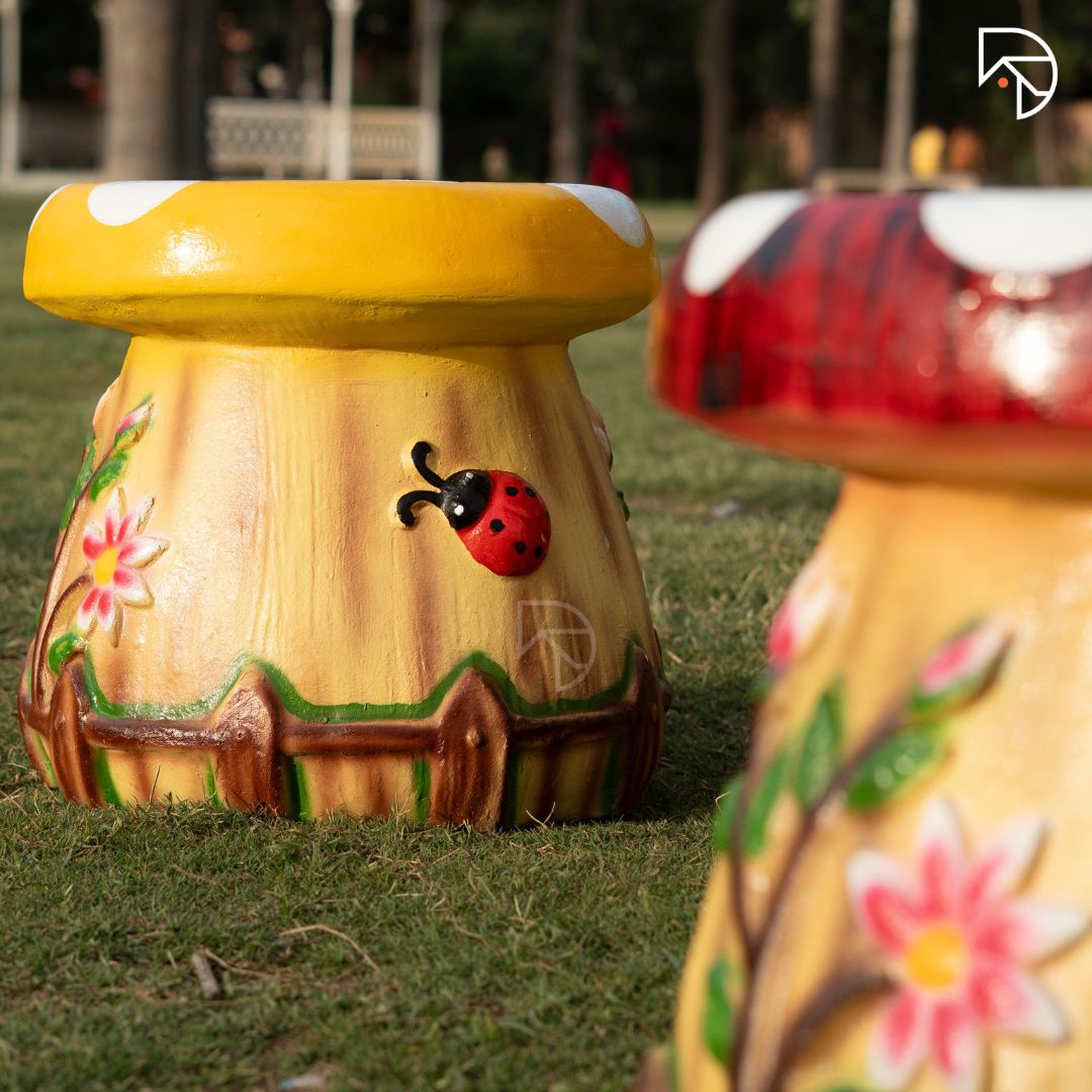 Decorative garden stool with floral and ladybug design on grass
