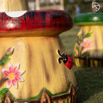 Decorative mushroom-shaped stool with floral and ladybug design on a grassy background