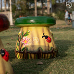 Decorative pot with floral and ladybug design on grass