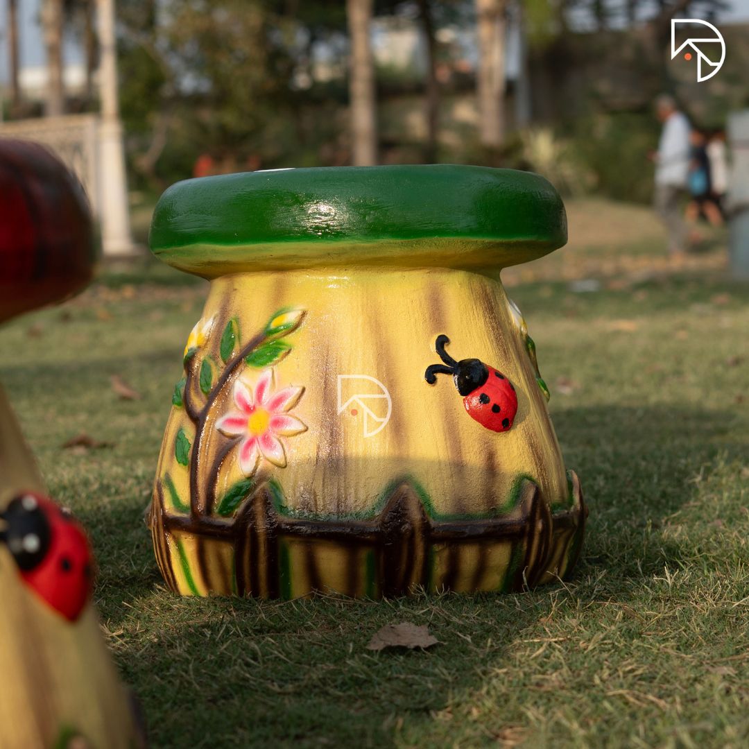 Decorative pot with floral and ladybug design on grass