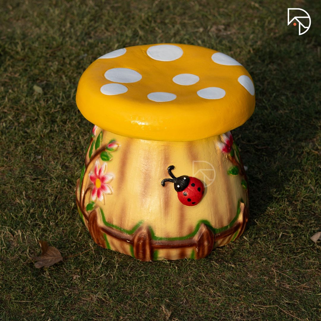 Decorative mushroom-shaped stool with a yellow cap and brown stem on grass