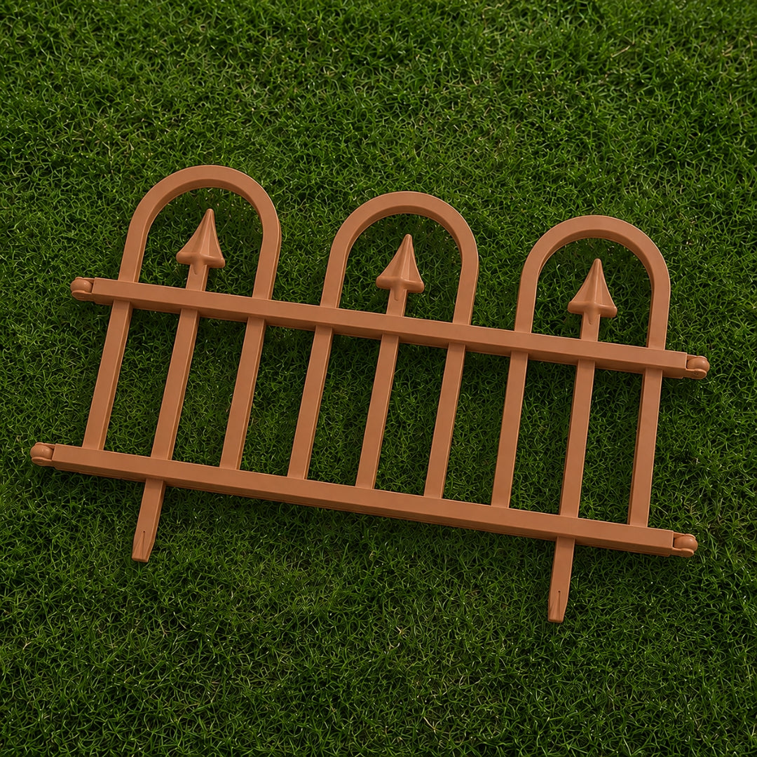A miniature brown plastic decorative fence with three arched tops and pointed finials, displayed on a green grass background.