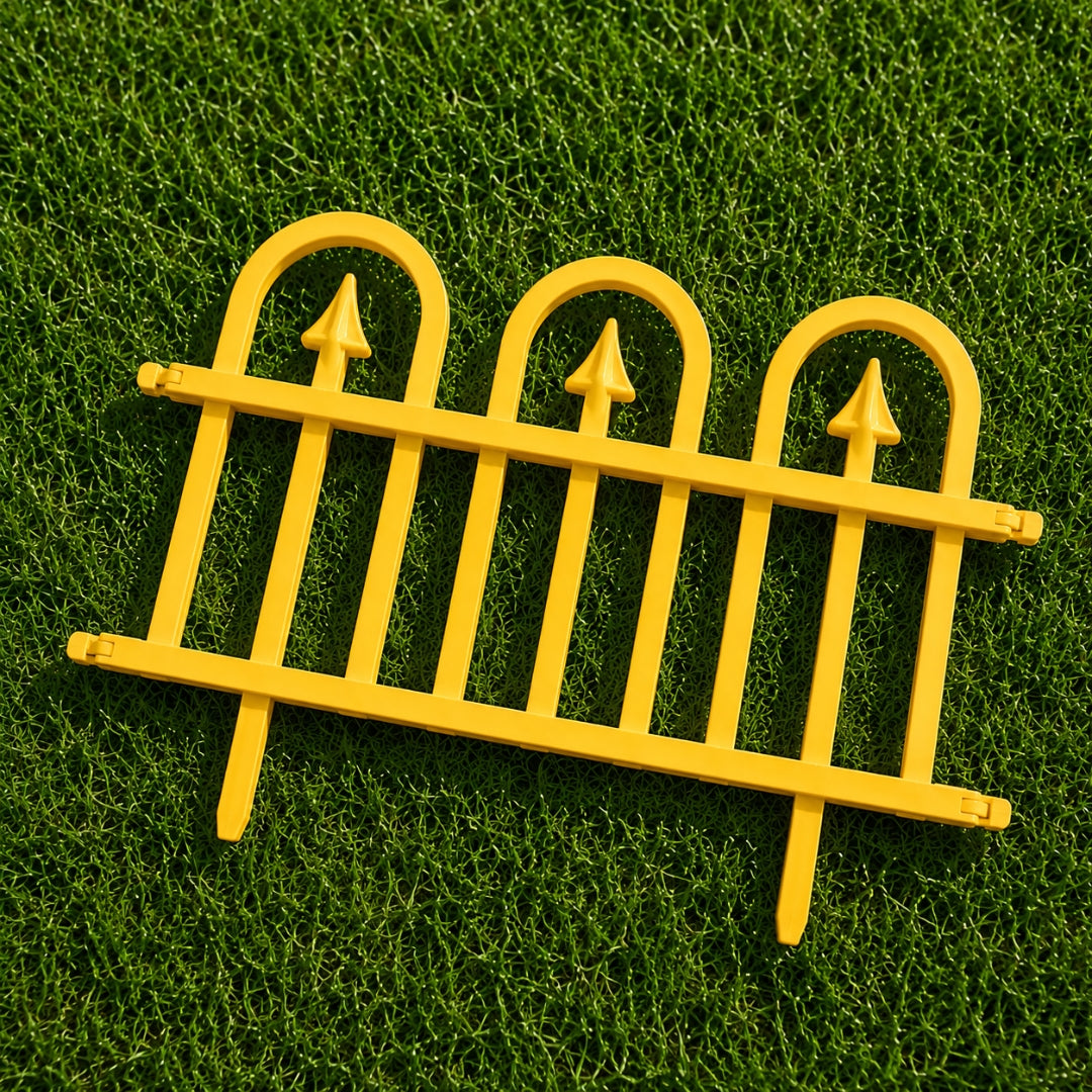A bright yellow miniature decorative fence panel with three arched tops and pointed finials, displayed on a green grass-like surface.