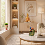 A beautifully styled living room featuring a light wood credenza with a gold Buddha statue on top, a marble coffee table in the foreground, and warm ambient lighting from a window and floor lamp.