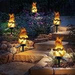 Solar rabbit lights on stakes in a garden setting with flowers and rocks.