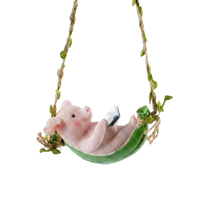 A small pink pig figurine reclining in a green leafy swing suspended by twine, shown against a plain white background.