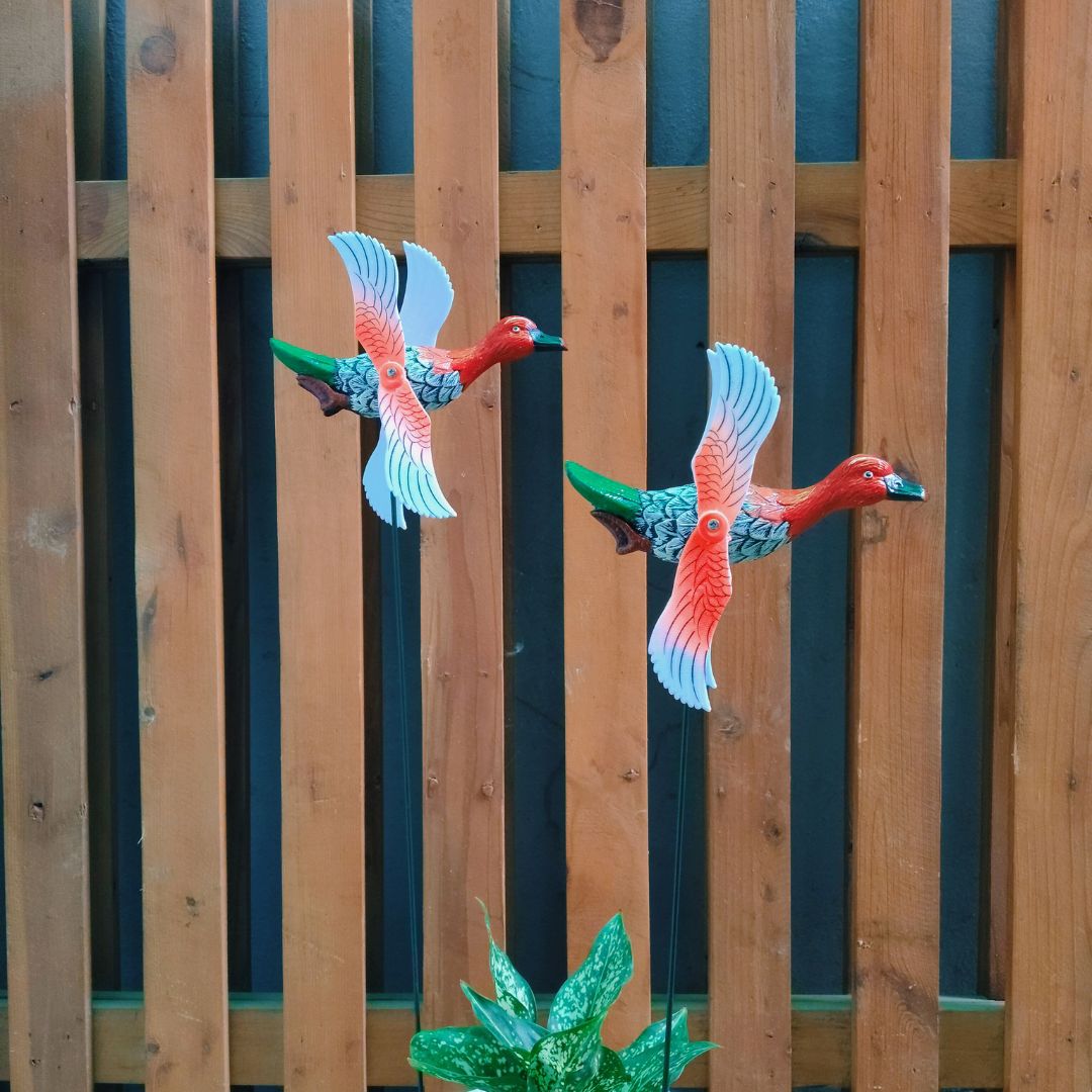 Two colorful bird figurines against a wooden fence background