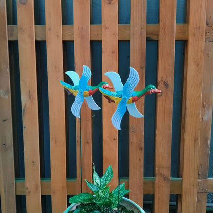 Colorful bird-shaped wind spinners against a wooden fence.