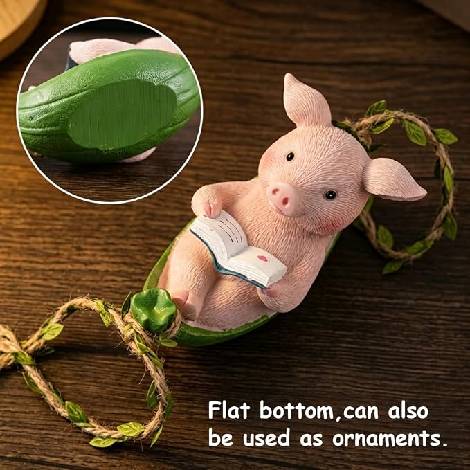 A small pig figurine sitting in a green pod and reading an open book, attached to a leafy vine wrapped in twine, shown on a dark wood surface. A circular inset highlights the green pod texture, and text at the bottom says the flat bottom can also be used as ornaments.