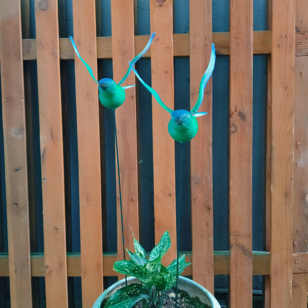 Decorative green antlers on a potted plant against a wooden fence background