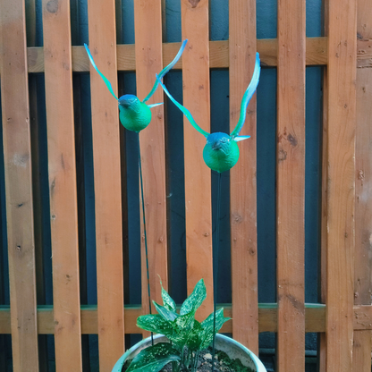Decorative green antlers on a potted plant against a wooden fence background