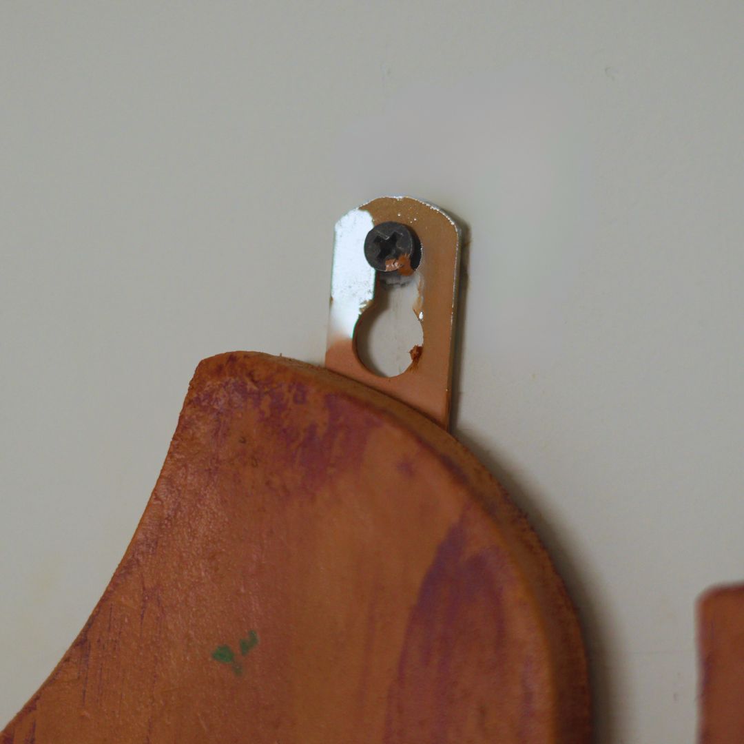 Wooden cutting board with a metal hook on a plain wall