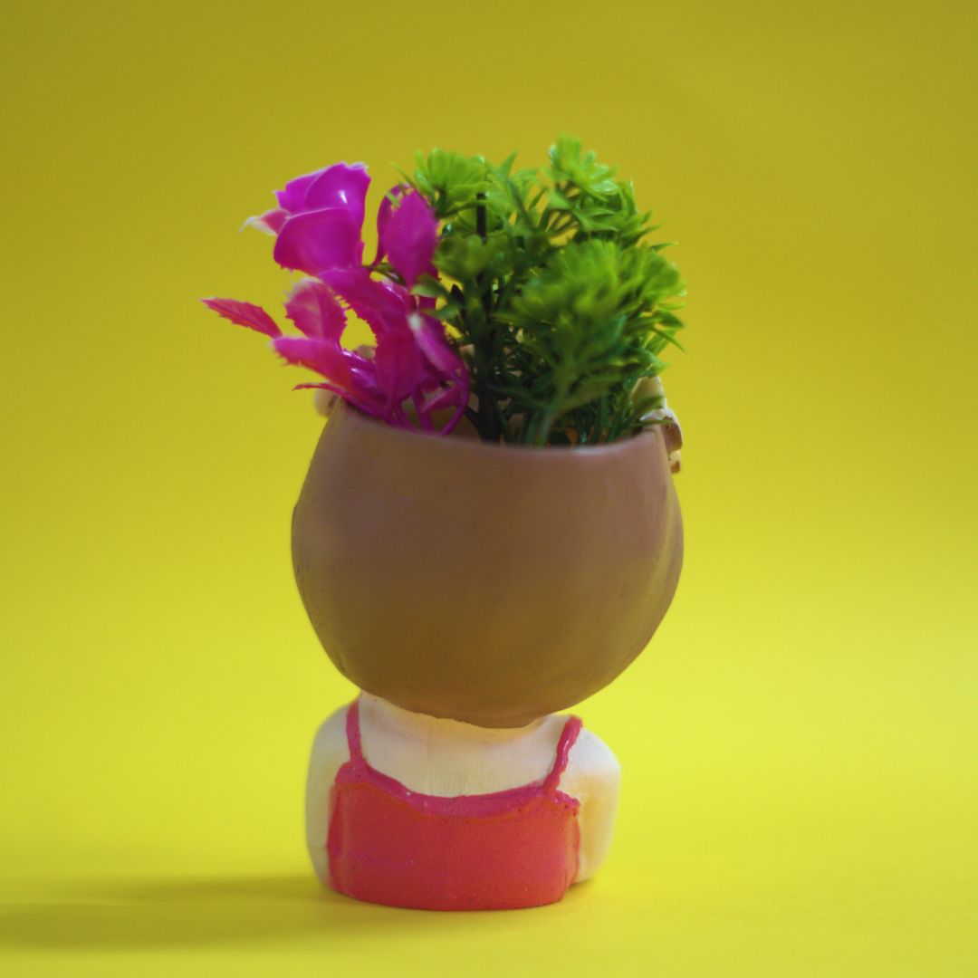 Small figurine with a pot of plants on a yellow background