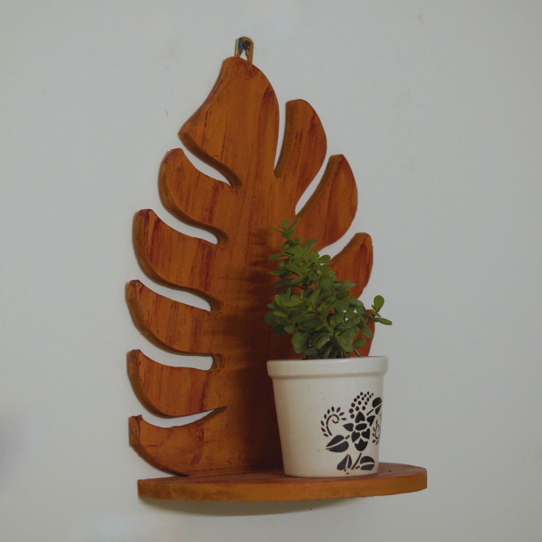 Wooden leaf-shaped shelf with a potted plant on a plain background