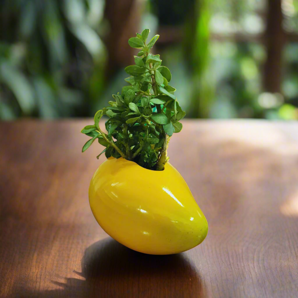 Yellow pear-shaped planter with a small green plant on a wooden surface