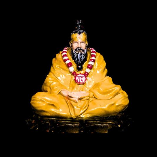 A colorful figurine of a Hindu god in a sitting pose, wearing a yellow garment and a decorative neck piece.