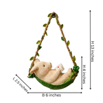 A hanging animal hammock ornament featuring a beige bunny lounging in a green hammock with leafy rope sides, shown with dimension labels on a white background.