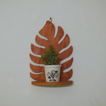 Wooden leaf-shaped shelf with a potted plant on a white wall