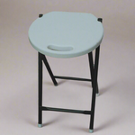 White stool with black legs on a wooden floor against a stone wall.