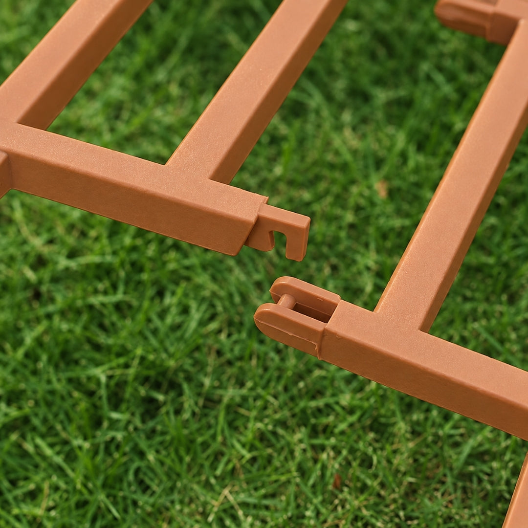 Close-up of terracotta-colored plastic frame pieces with interlocking tabs, shown outdoors on a green grass background.